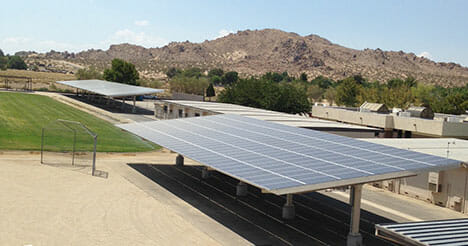 Photo of solar panel canopies over a parking lot in front of a mountain