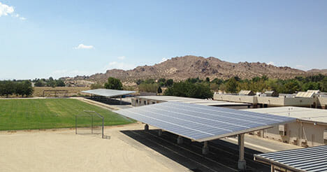 Photo of solar panel canopies over a parking lot in front of a mountain