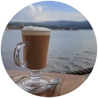 coffee in a glass mug with a bay behind it