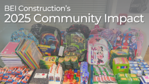 A table filled with donated school supplies, including colorful backpacks, notebooks, folders, glue bottles, pencils, crayons, markers, scissors, and sharpeners, arranged for BEI Construction’s Back-to-School Drive.